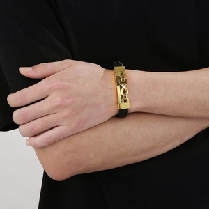 Detail of men's black braided leather bracelet with gold metal buckle on wrist