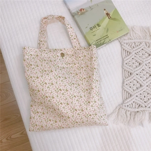 Vue détaillée de dessus d'un mini sac cabas en toile fleurie crème avec fermoir