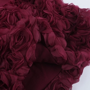 Gros plan sur le tissu en maille rouge vin à roses 3D avec détails floraux délicats