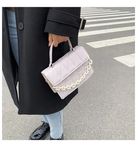 Vue détaillée du sac matelassé lilas avec chaîne blanche décorative et poignée supérieure