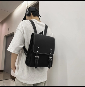 Rear view of model wearing a vintage black leather backpack with metal buckles