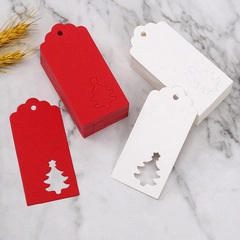 Detail of red and white heart-shaped kraft paper tags with Christmas tree cutout on marble