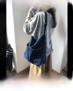 Detail of a large dark blue denim tote bag with soft texture and wide shoulder strap