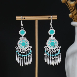 Detail view of silver bohemian tassel earrings with turquoise beads on a display stand