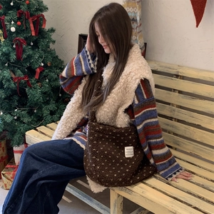 Detail of plush brown polka dot crossbody tote bag shown in a cozy winter setting