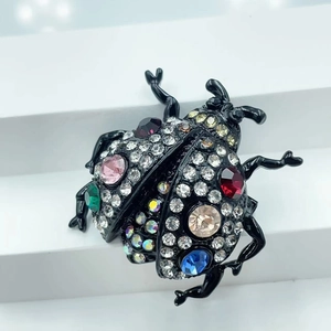 Macro shot of colorful rhinestone beetle brooch with pink and blue stones on black base