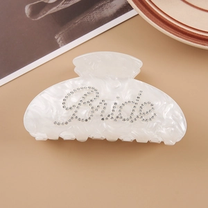 Detailed shot of pearly white marble hair claw clip with crystal Bride lettering decor