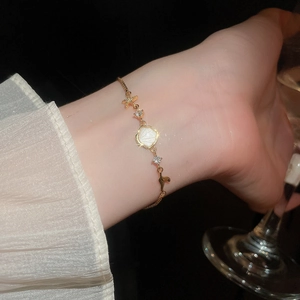 Detailed shot of a gold ocean bracelet with shell and starfish charms on a wrist