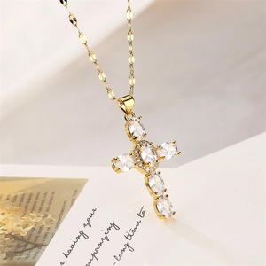 Close-up of a gold cross pendant necklace featuring oval and round cubic zirconia stones