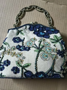 Detailed view of floral beadwork embroidery on a vintage linen evening handbag frame