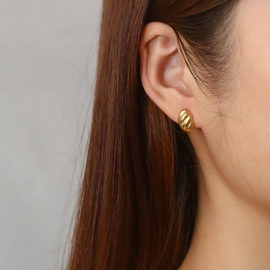 Close-up of golden vintage croissant earrings with spiral textured finish on model