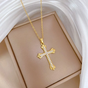 Close-up of golden stainless steel cross pendant necklace with sparkling zircon stones