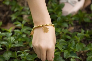 Detail of gold beaded stretch bracelet with Hamsa Hand charm on woman's wrist