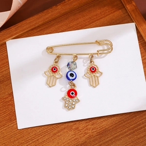 Detail of gold evil eye and Hamsa hand tassel brooch with blue crystals and rhinestones