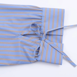 Vista detallada de la manga de la camisa a rayas con un lazo decorativo en los puños