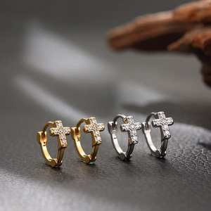 Gros plan de boucles d'oreilles créoles croix en or et argent avec zircons brillants