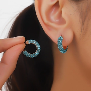 Detail shot of rose gold hoop earrings with pavé sky blue crystals on a model