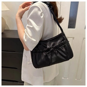 Détail du sac à bandoulière noir plissé avec nœud décoratif porté par un mannequin