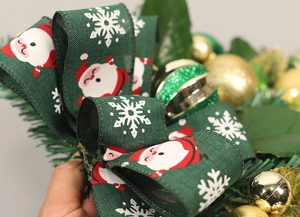 Close-up of Christmas PVC green ribbon with red Santa print and gold bauble ornaments