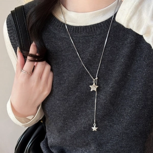 Detail of silver Y-shape necklace with double star pendant on grey knitwear sweater