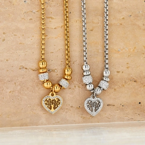 Gold and silver heart Tree of Life necklaces with cubic zirconia on marble background