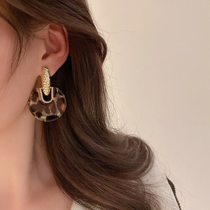 Close-up of vintage leopard print acrylic hoop earring with textured golden stud