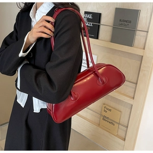 Detailed side view of a large red PU leather underarm bag worn with a black blazer