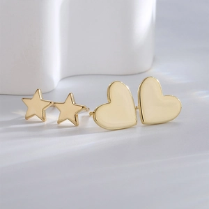Elegant gold-plated star and heart stud earrings set on a minimalist background