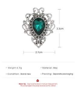 Detail showing an emerald glass brooch with antique silver alloy frame and product dimensions