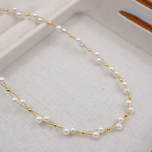 Elegant woven pearl and gold bead layered necklace on a soft textured background