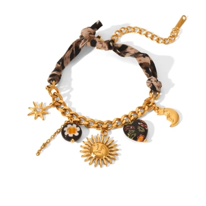 Detail of gold bracelet featuring leopard print fabric knot with sun and star charms