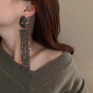 Close-up of dangling water-drop rhinestone tassel earrings on a model with shimmering crystals