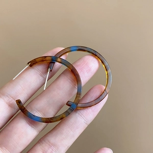 Macro shot of tortoiseshell C-shaped resin earrings with blue amber resin textures