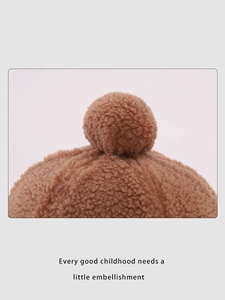 Detail of the brown sherpa fleece texture and plush pom-pom on top of children's warm hat