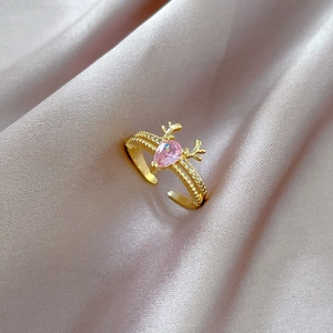 Macro detail of golden reindeer ring featuring a pink teardrop zircon on pink silk fabric