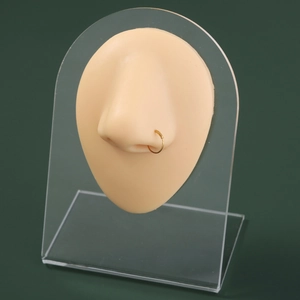 Detailed view of a gold-toned U-shaped nose ring displayed on a silicone model piercing