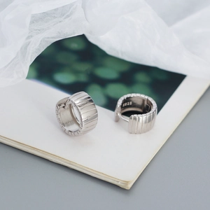 Macro detail of silver S925 sterling silver hoop earrings with vertical stripe relief texture
