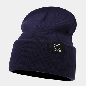 Détail montrant la maille côtelée et le patch double cœur sur le bonnet bleu marine