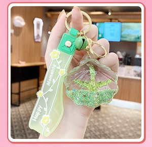 Close-up of shell-shaped green liquid glitter keychain with a bell on a gold ring