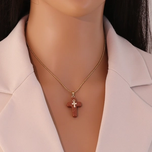 Close-up of gold titanium necklace with a reddish-brown natural stone cross pendant
