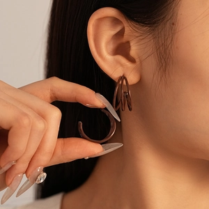 Detail view of coffee brown multi-layer spiral C-shaped geometric stud earrings on model