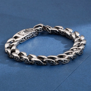 Macro view of vintage stainless steel bracelet featuring intricate floral pattern engraving