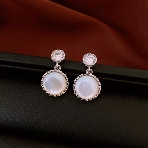 Macro view of vintage silver zircon earrings with white resin inlay on black stand