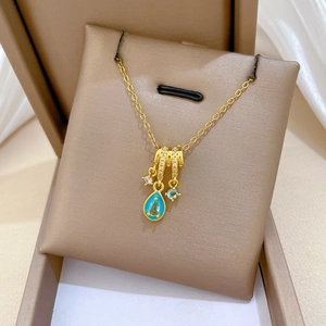 Detail of gold necklace with blue teardrop and round crystal pendants in a jewelry box