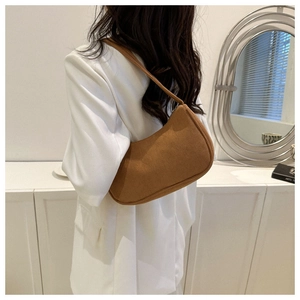 Detailed view of brown corduroy baguette shoulder bag worn over a white blazer