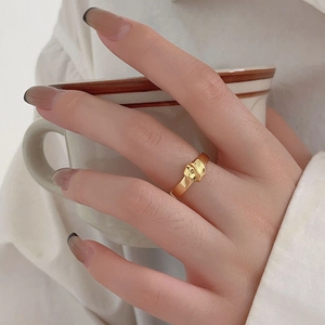 Close-up of a minimalist gold knot ring on model's finger with a ceramic cup background