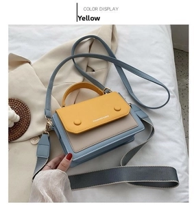 Detailed close-up of yellow and blue color-blocked handbag with decorative strap
