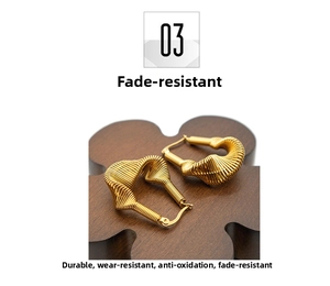 Detail view of gold-plated stainless steel earrings with twisted spiral texture on wood