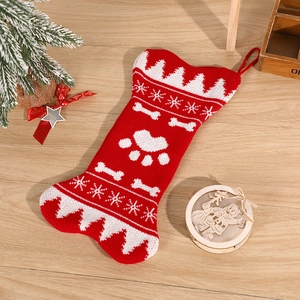 Red and white knitted bone-shaped Christmas stocking with paw prints on wooden floor