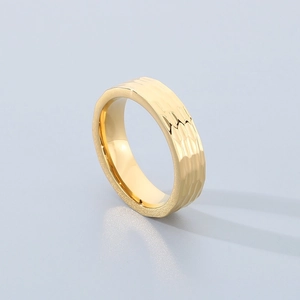 Detail of wide golden titanium ring with hammered texture and polished finish